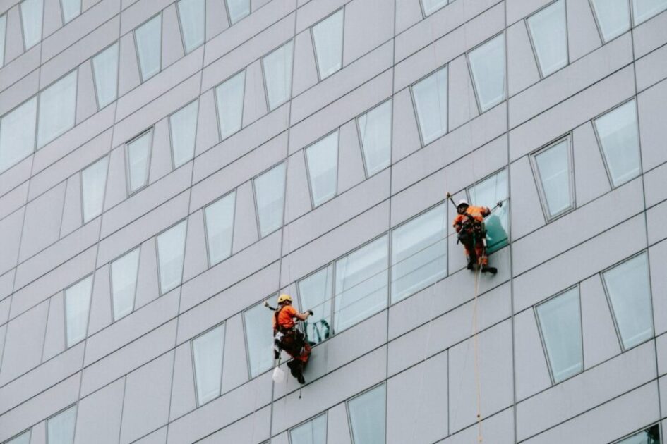 two male rope access workers washing the windows of a modern building