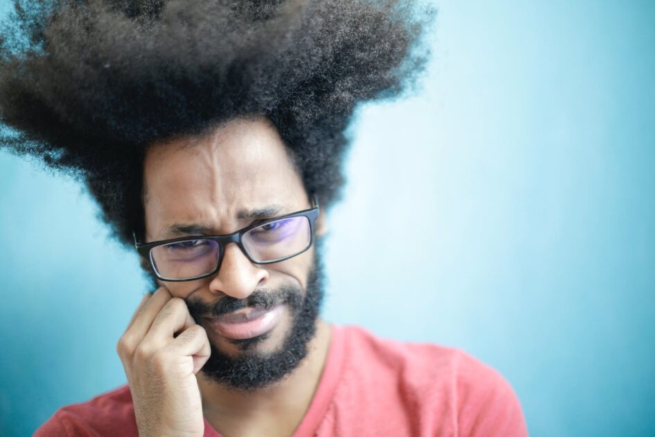 frustrated ethnic man in casual wear on blue background in studio